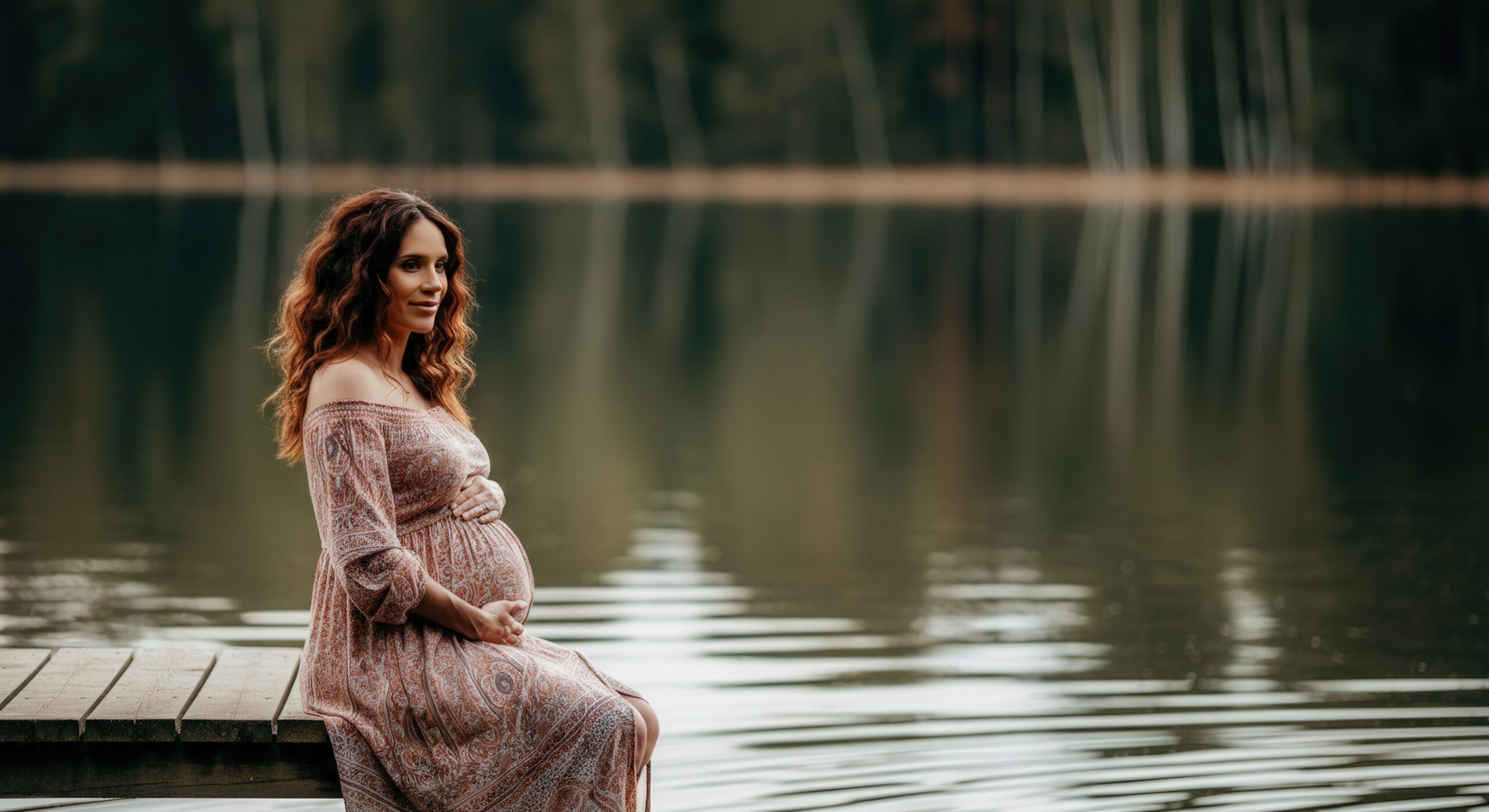 Pregnant woman by a lake, quietly reflective